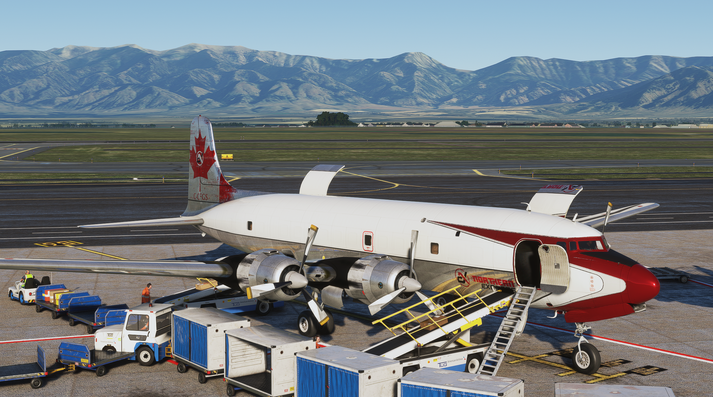 Classic aircraft being serviced with mountains behind the airport